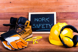 work boots, gloves, helmet and sign that says "Work Safety"