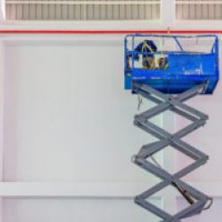 Scissor lift platform with hydraulic system elevated towards a factory roof with construction workers, Mobile aerial work platform