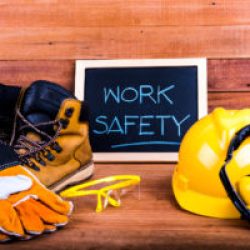 work boots, gloves, helmet and sign that says "Work Safety"